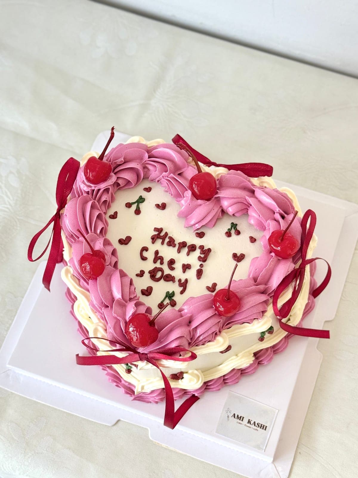 Heart cake piped in pink with cherries and red ribbon bows